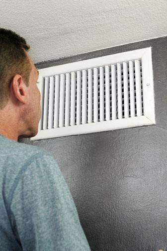 man inspecting an HVAC duct register